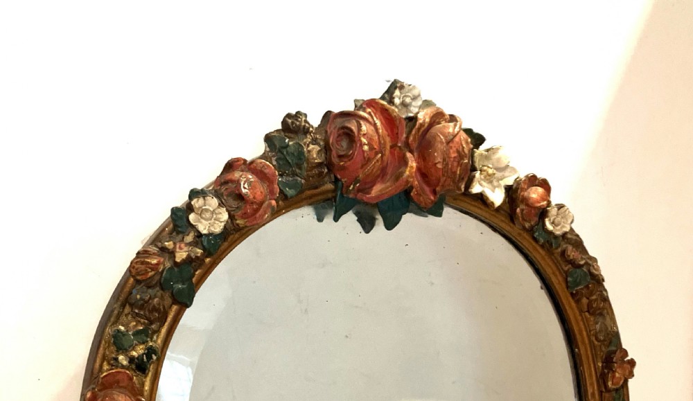 An arched wall mirror featuring a bevelled glass plate framed by a gilded mould with polychrome painted plaster roses at the top. View II