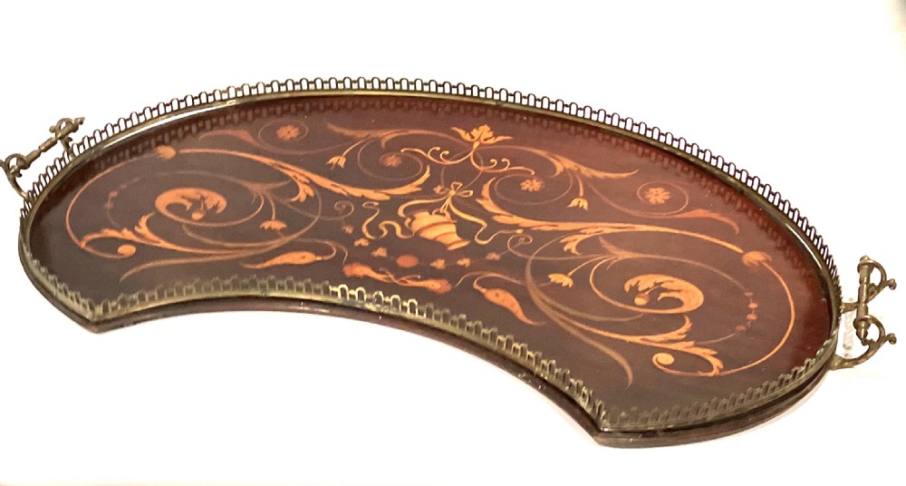 A crescent-shaped mahogany tray featuring inlaid botanical marquetry, a central urn motif, and a pierced brass gallery rim with handles.