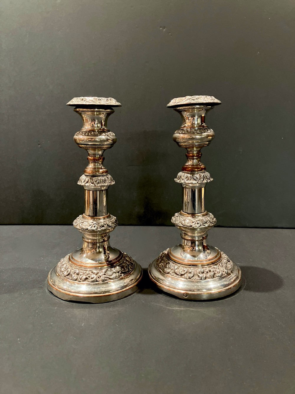 A pair of silver-plated telescopic candlesticks featuring circular embossed bases and adjustable stems.