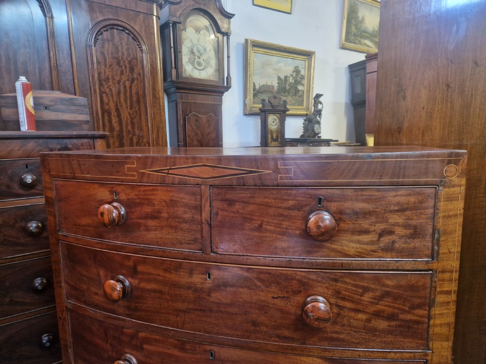 A Georgian mahogany bow front chest of drawers featuring two short over three long graduated drawers with turned wooden knobs and delicate geometric inlay. View III