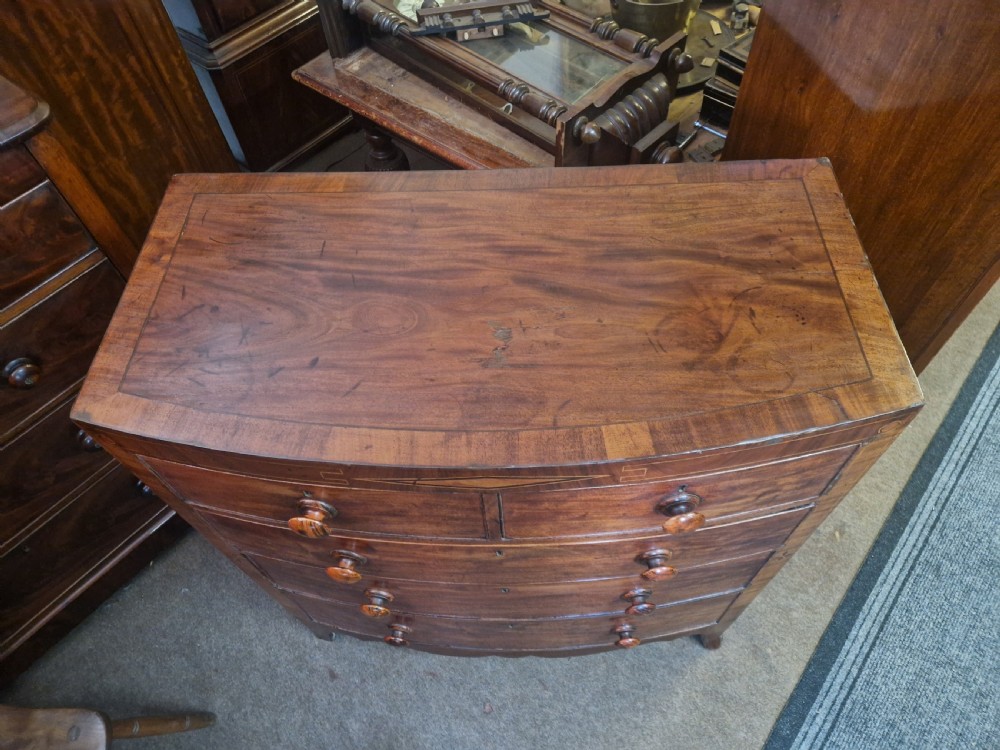 A Georgian mahogany bow front chest of drawers featuring two short over three long graduated drawers with turned wooden knobs and delicate geometric inlay. View V