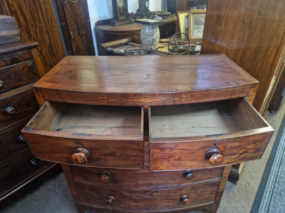 A Georgian mahogany bow front chest of drawers featuring two short over three long graduated drawers with turned wooden knobs and delicate geometric inlay. View VI