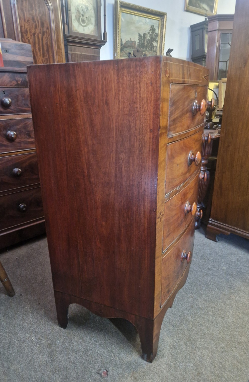 A Georgian mahogany bow front chest of drawers featuring two short over three long graduated drawers with turned wooden knobs and delicate geometric inlay. View X