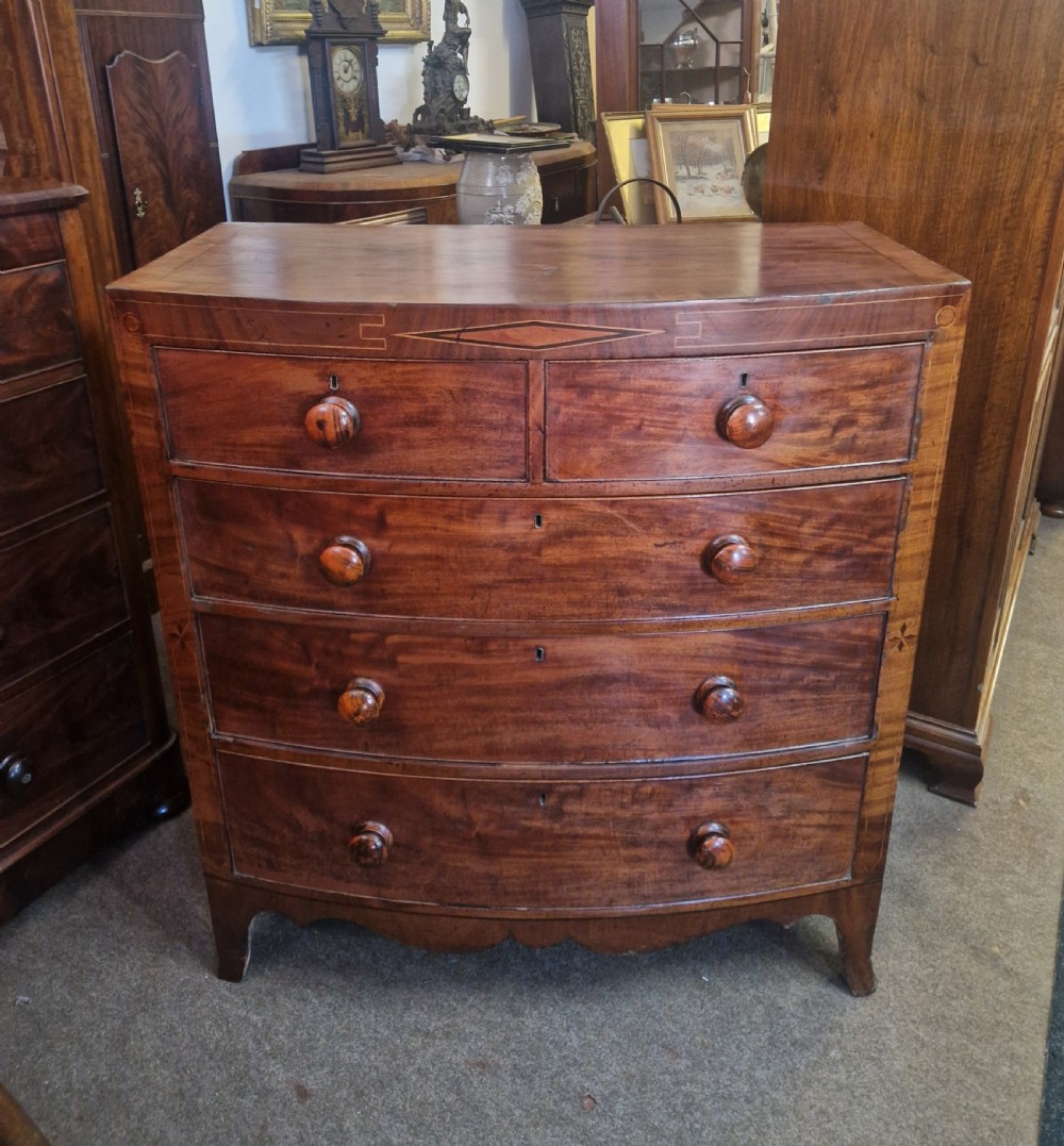 A Georgian mahogany bow front chest of drawers featuring two short over three long graduated drawers with turned wooden knobs and delicate geometric inlay. View XII