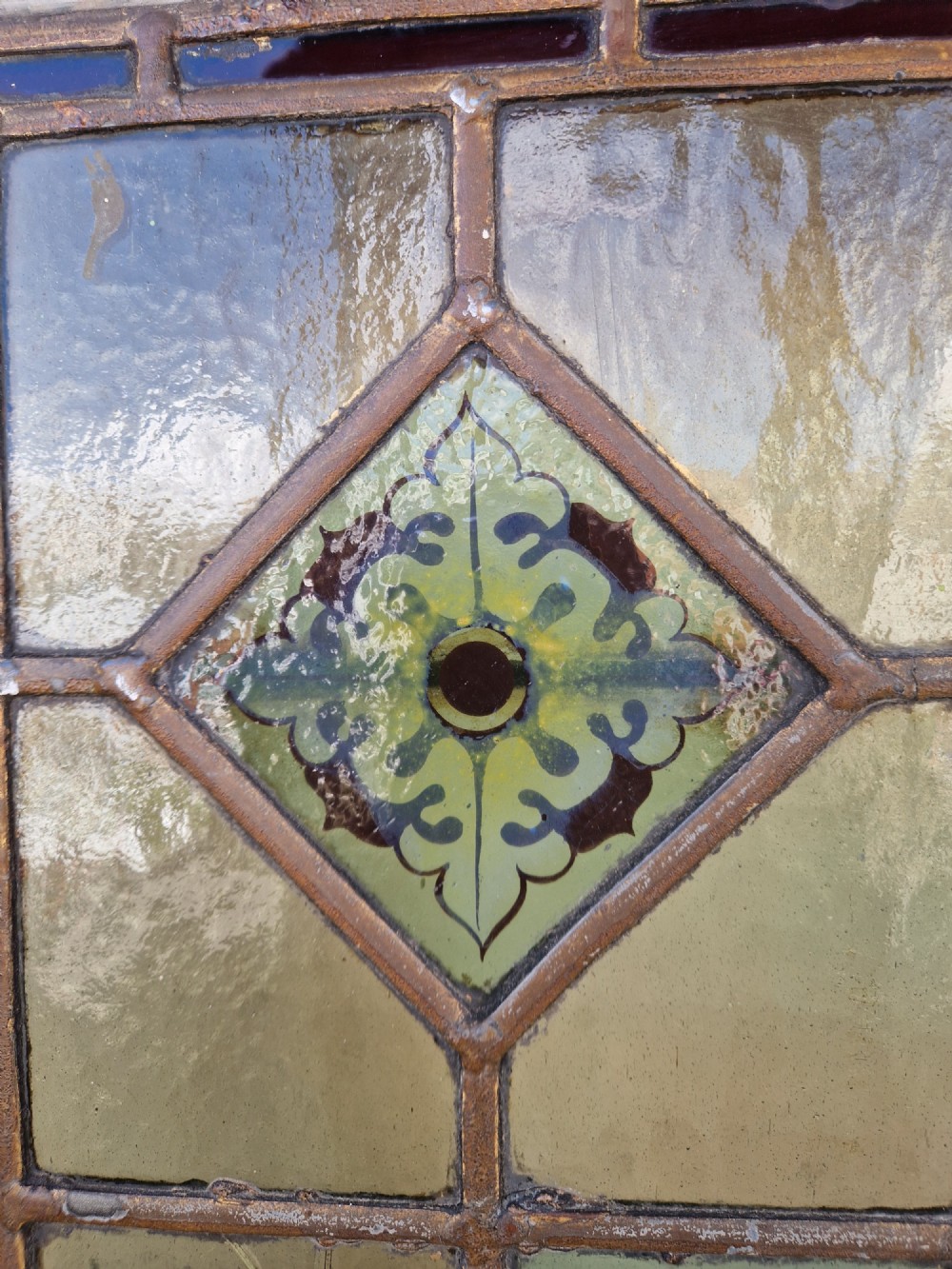 A rectangular Victorian leaded glass panel set in a timber frame, featuring pastel geometric panes, four decorative corner inserts, and a central roundel depicting a hand-painted bird. View VIII