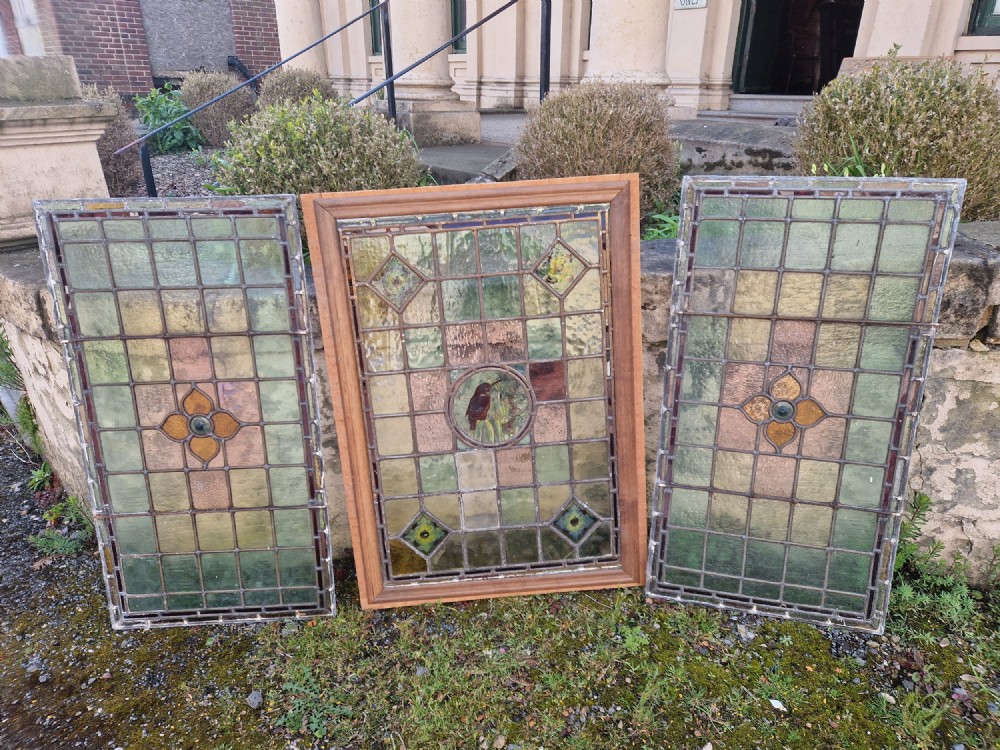 A rectangular Victorian leaded glass panel set in a timber frame, featuring pastel geometric panes, four decorative corner inserts, and a central roundel depicting a hand-painted bird. View XII