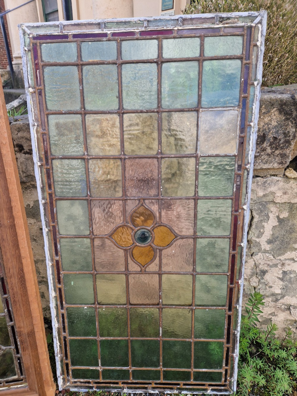 A rectangular Victorian leaded glass panel set in a timber frame, featuring pastel geometric panes, four decorative corner inserts, and a central roundel depicting a hand-painted bird. View XIV