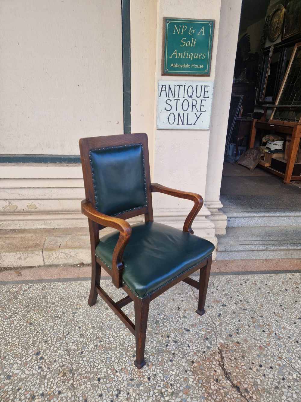 An antique Arts and Crafts oak armchair featuring dark green leather upholstery secured with decorative metal studs. View II