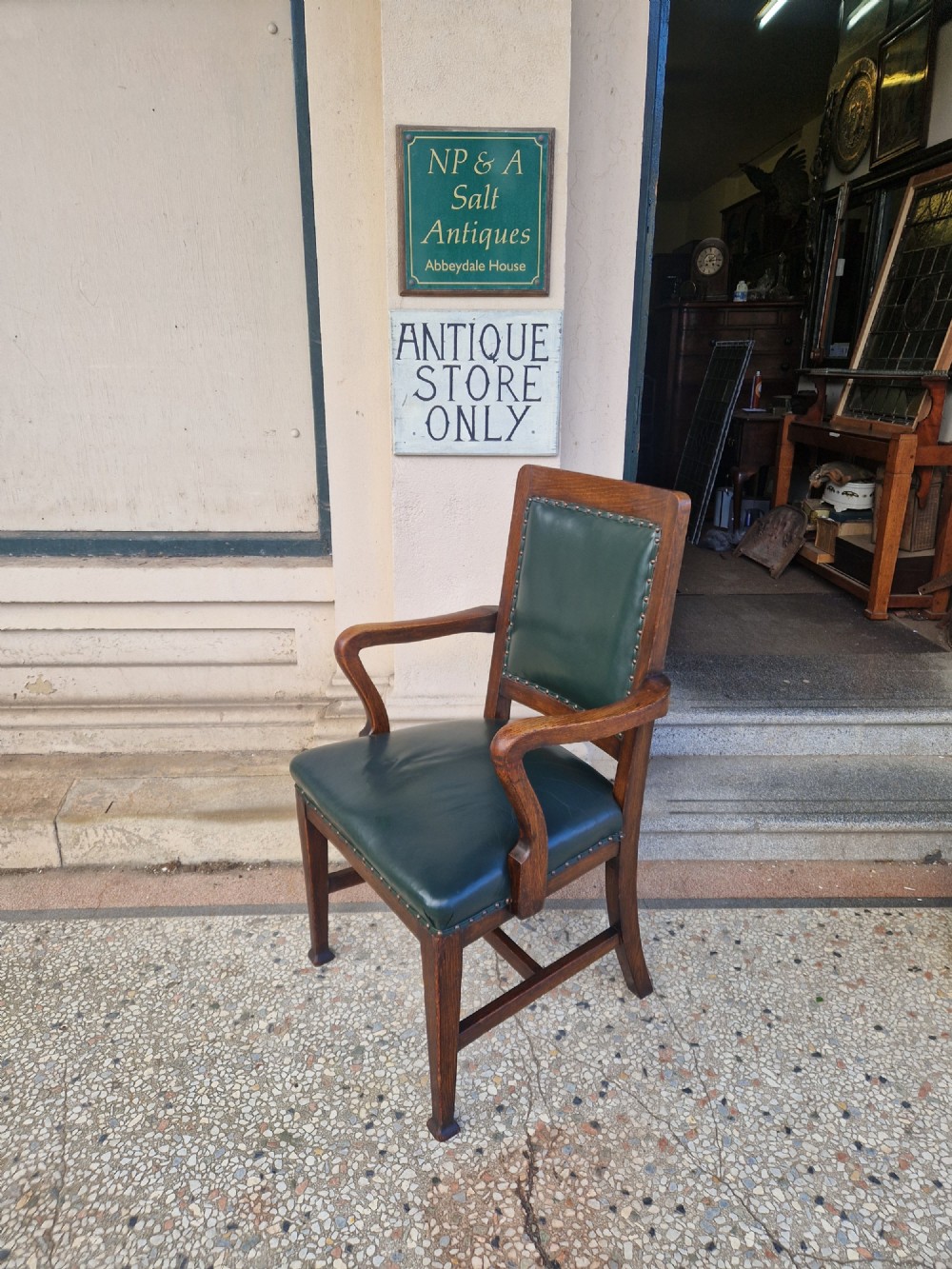 An antique Arts and Crafts oak armchair featuring dark green leather upholstery secured with decorative metal studs. View III