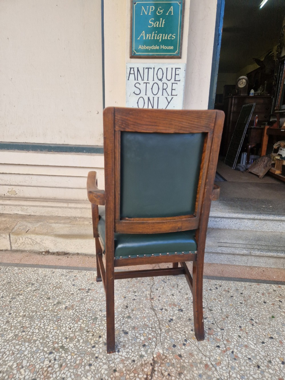 An antique Arts and Crafts oak armchair featuring dark green leather upholstery secured with decorative metal studs. View IV