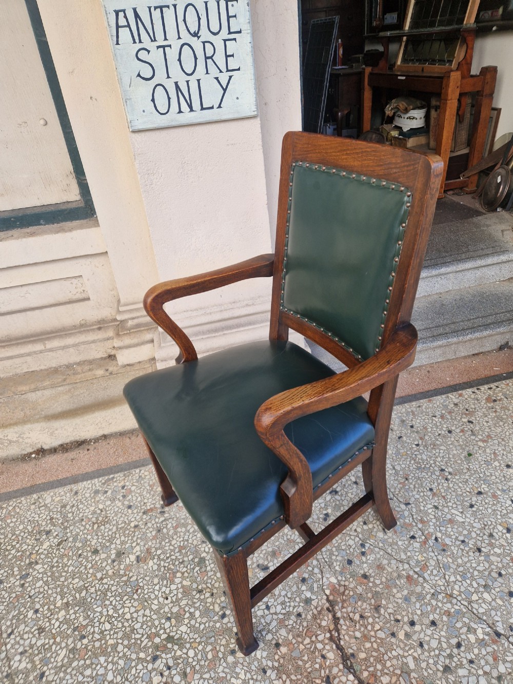 An antique Arts and Crafts oak armchair featuring dark green leather upholstery secured with decorative metal studs. View V