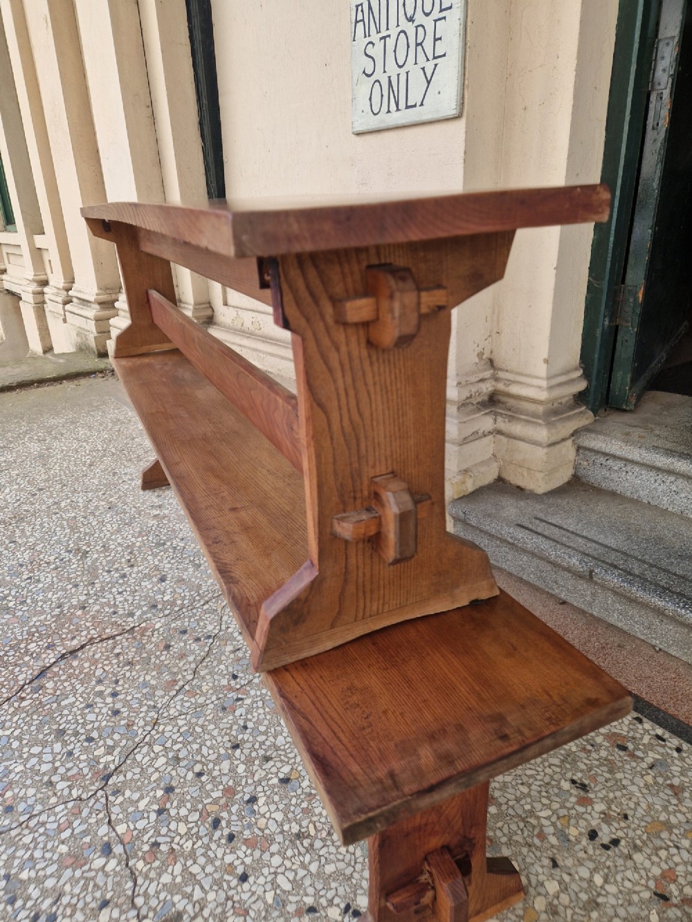 A pair of long solid oak benches featuring flat plank tops, trestle legs, and horizontal wooden stretchers. View III