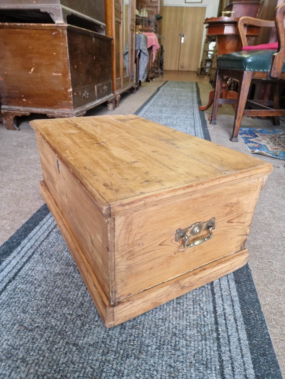 A rectangular antique pine storage box with a hinged lid, tapered sides, a moulded base, and an iron keyhole escutcheon on the front. View II