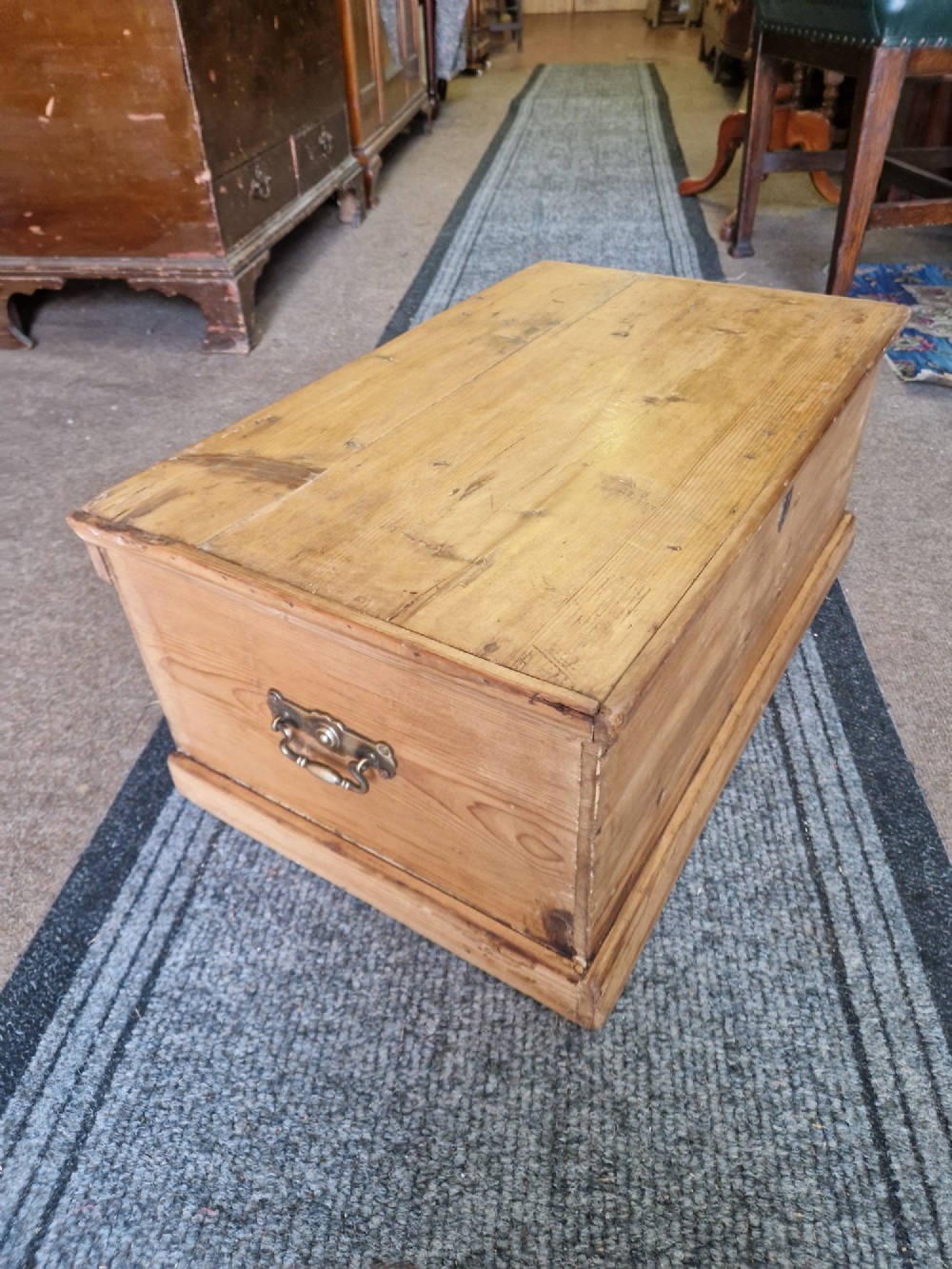 A rectangular antique pine storage box with a hinged lid, tapered sides, a moulded base, and an iron keyhole escutcheon on the front. View IV