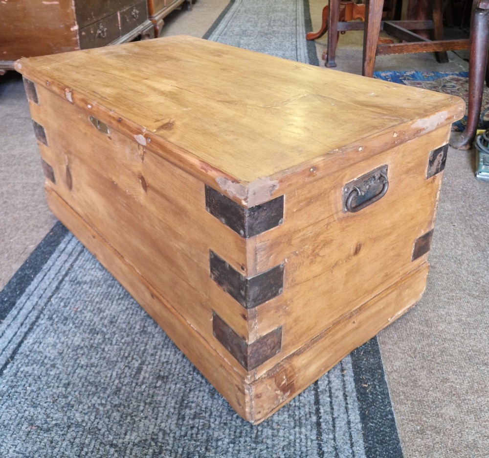 An antique pine blanket box featuring iron corner straps, a brass keyhole escutcheon, and a hinged lid. View III
