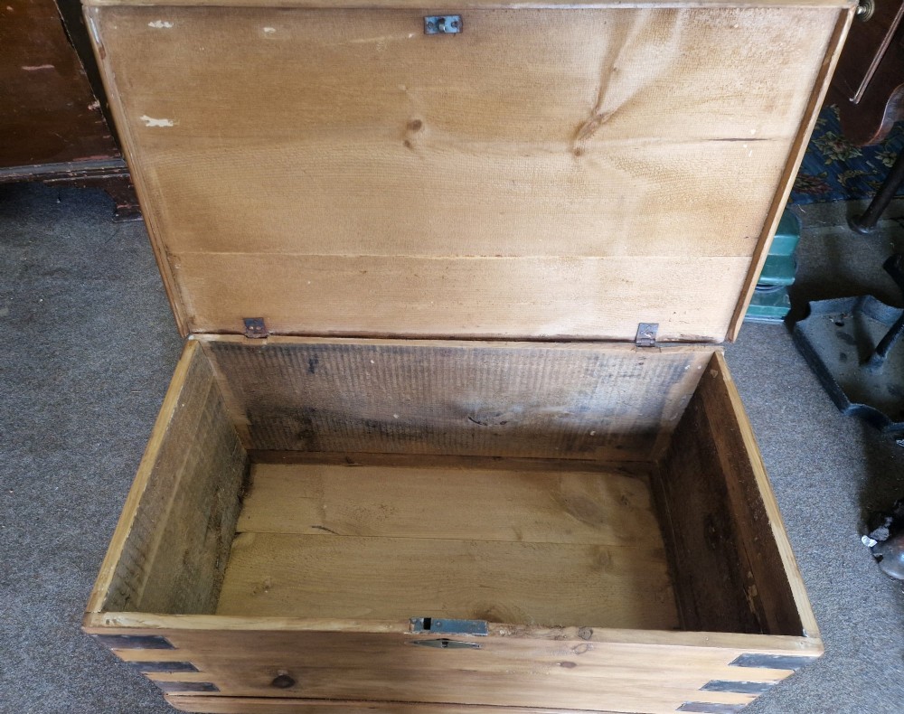 An antique pine blanket box featuring iron corner straps, a brass keyhole escutcheon, and a hinged lid. View V