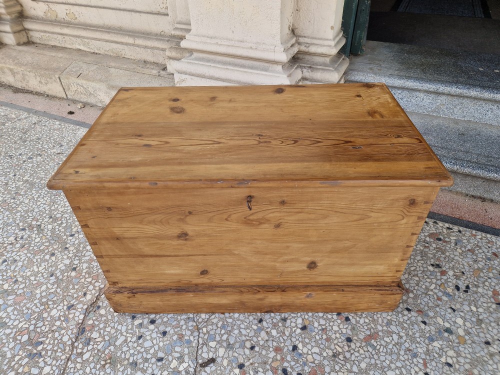 A rectangular Victorian pine blanket box featuring a hinged top lid, visible dovetail joints at the corners, and a solid plinth base.