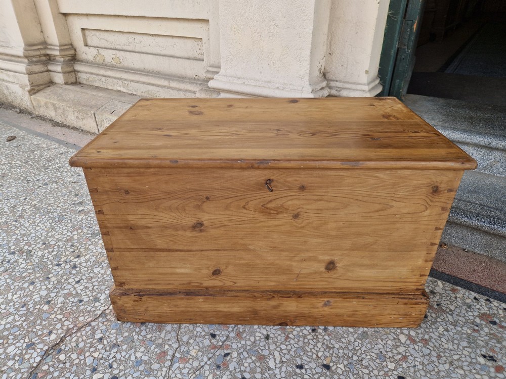 A rectangular Victorian pine blanket box featuring a hinged top lid, visible dovetail joints at the corners, and a solid plinth base. View V