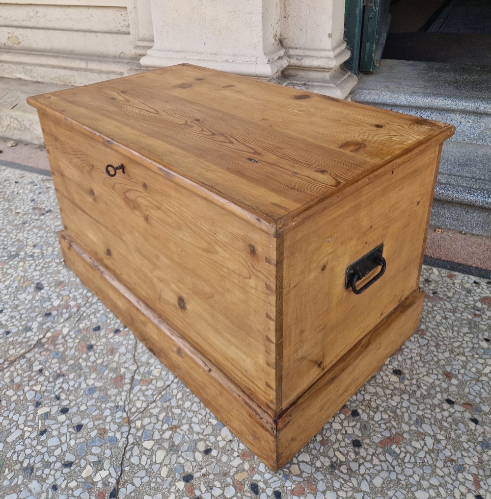 A rectangular Victorian pine blanket box featuring a hinged top lid, visible dovetail joints at the corners, and a solid plinth base. View VI