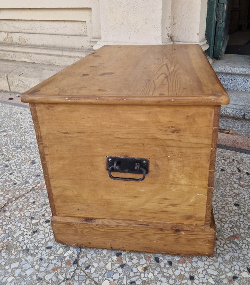 A rectangular Victorian pine blanket box featuring a hinged top lid, visible dovetail joints at the corners, and a solid plinth base. View VIII