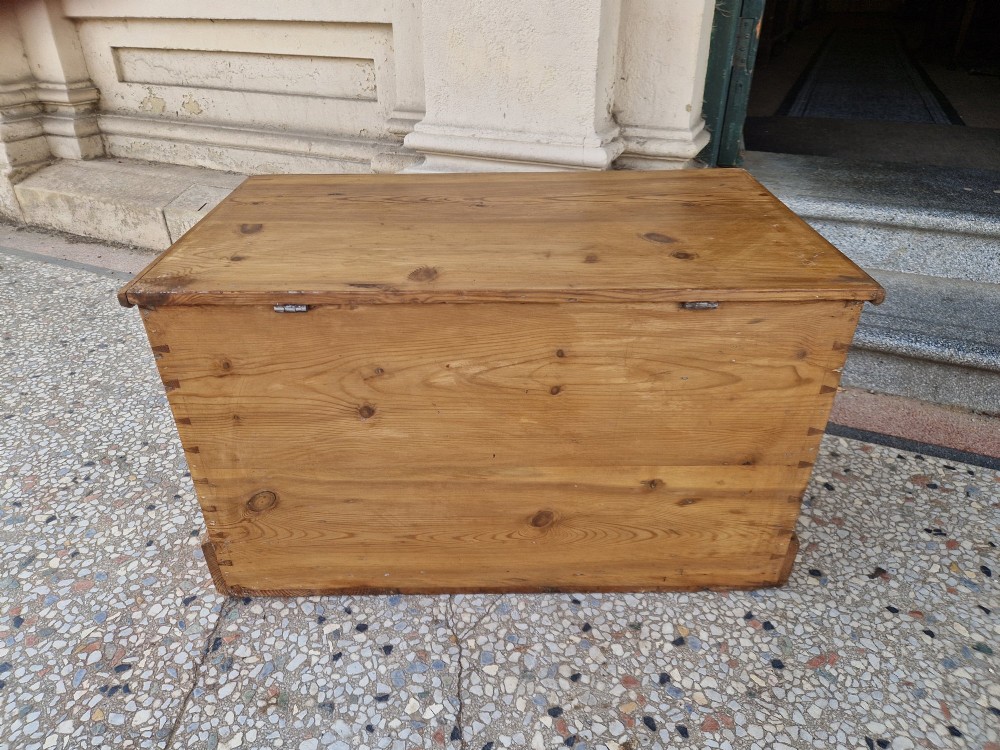 A rectangular Victorian pine blanket box featuring a hinged top lid, visible dovetail joints at the corners, and a solid plinth base. View X