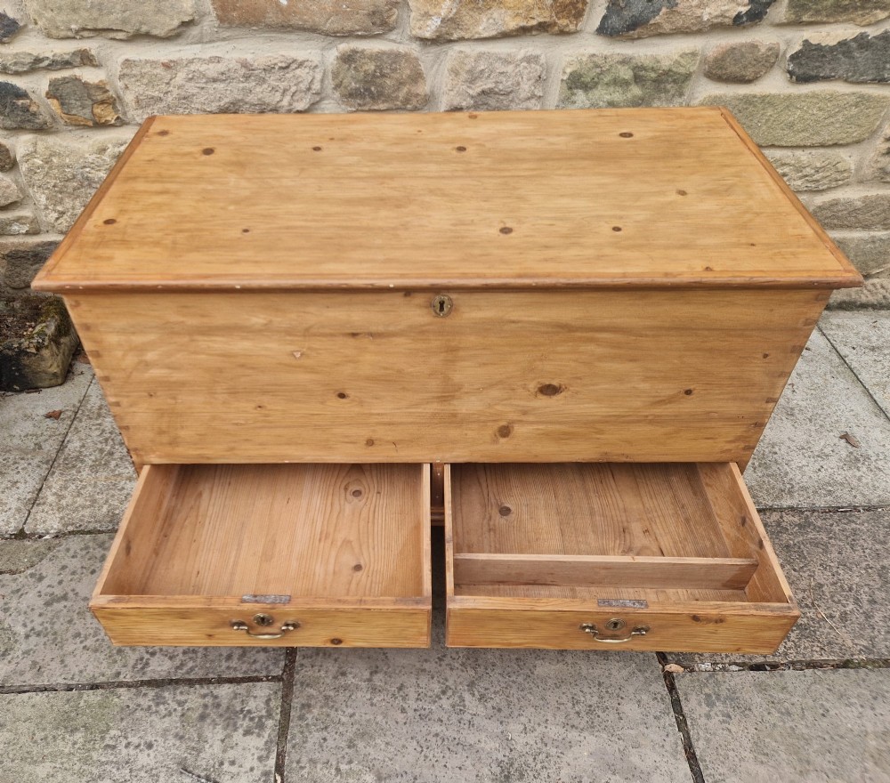 An antique Georgian pine mule chest featuring a lift-top lid, two lower drawers with brass drop handles, visible corner dovetail joints, and bracket feet. View II