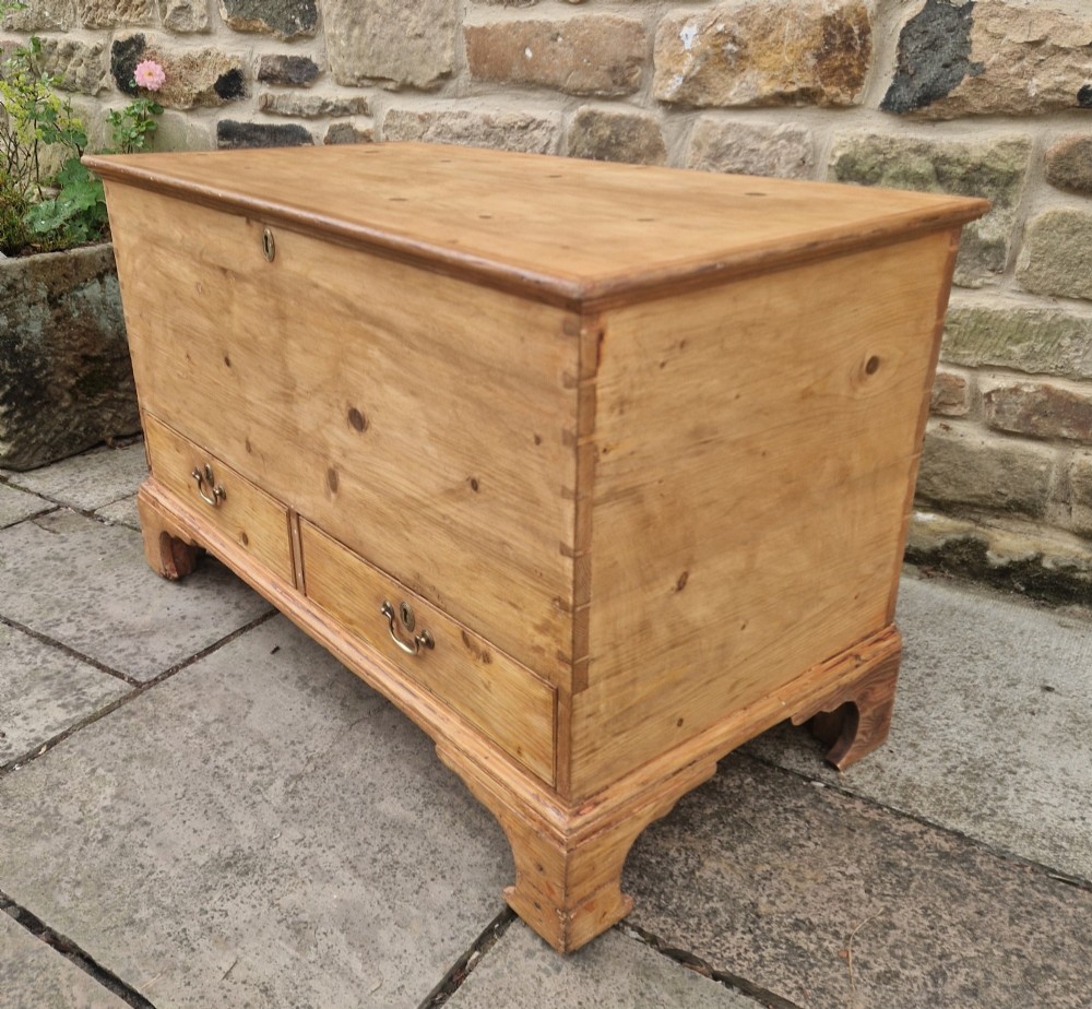 An antique Georgian pine mule chest featuring a lift-top lid, two lower drawers with brass drop handles, visible corner dovetail joints, and bracket feet. View III