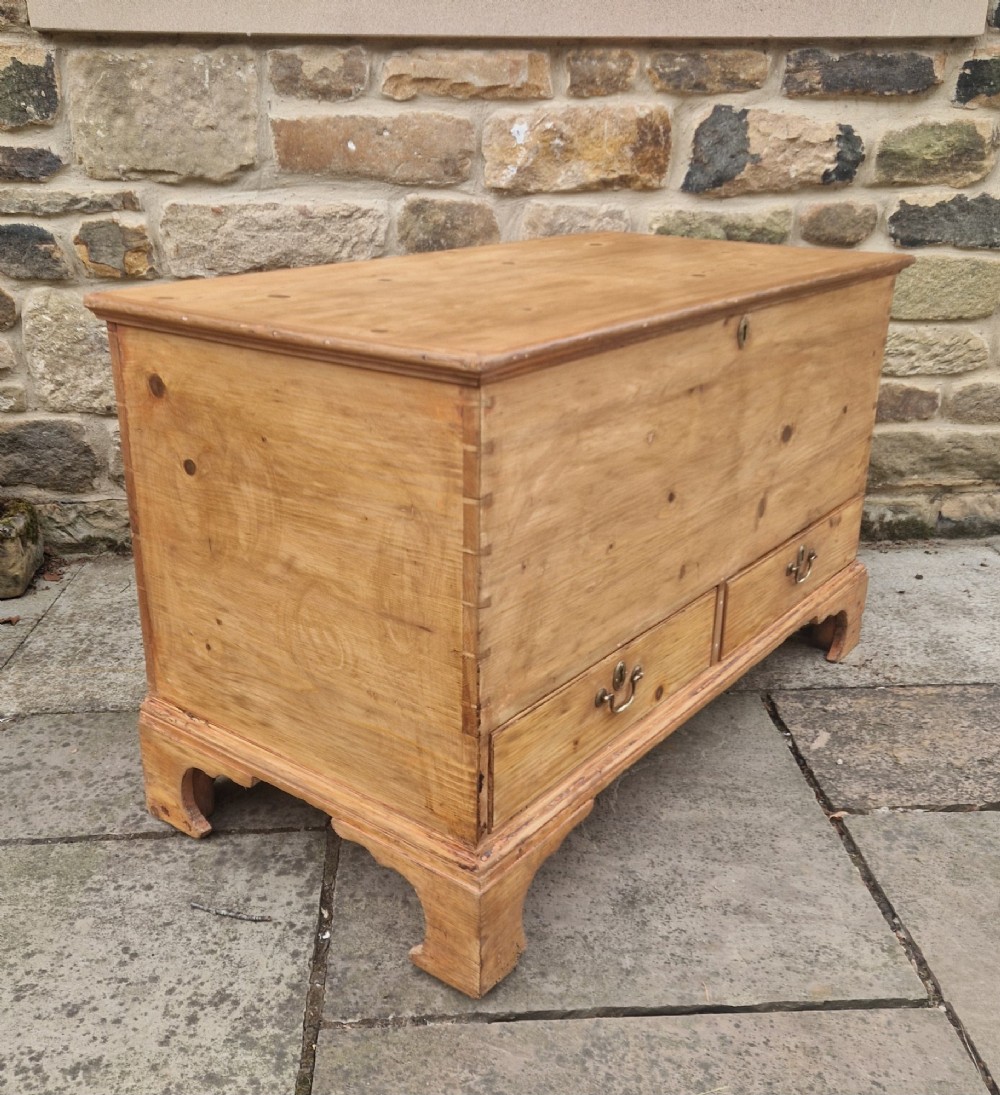 An antique Georgian pine mule chest featuring a lift-top lid, two lower drawers with brass drop handles, visible corner dovetail joints, and bracket feet. View IV