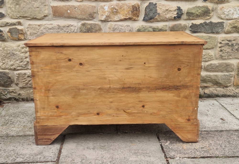 An antique Georgian pine mule chest featuring a lift-top lid, two lower drawers with brass drop handles, visible corner dovetail joints, and bracket feet. View VII