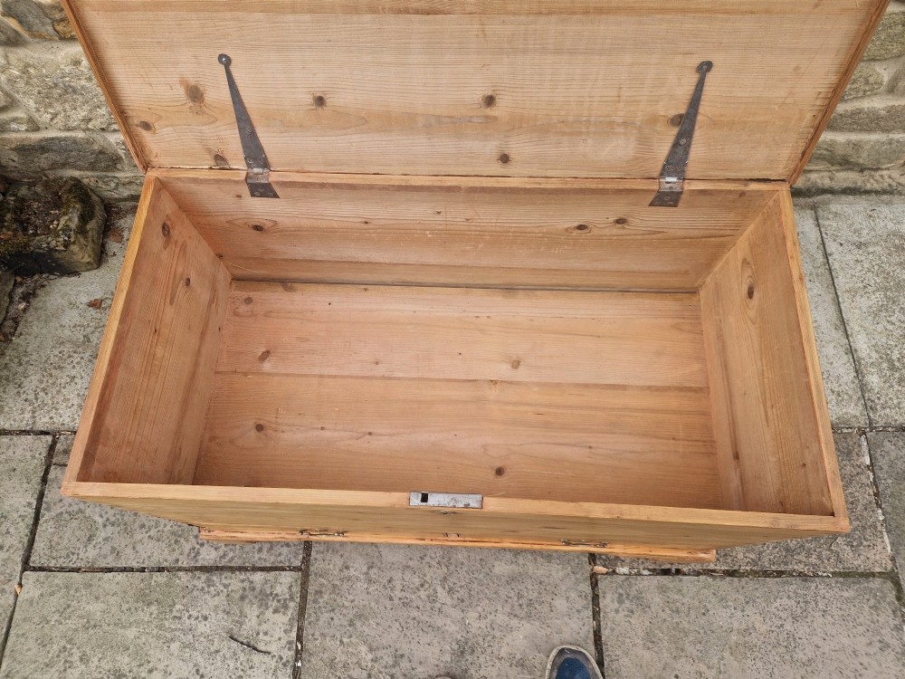 An antique Georgian pine mule chest featuring a lift-top lid, two lower drawers with brass drop handles, visible corner dovetail joints, and bracket feet. View VI