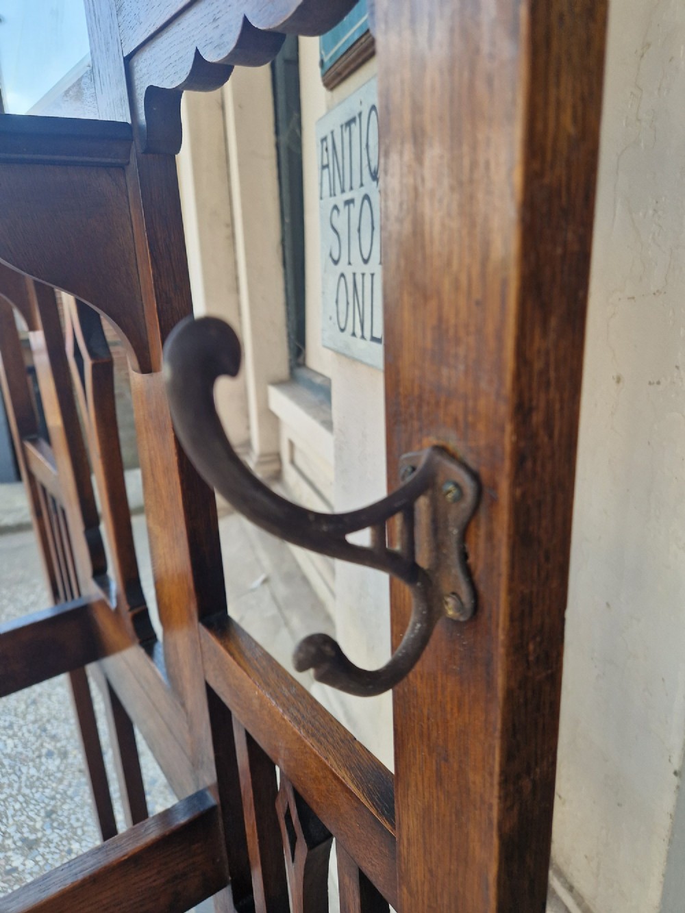 An Art Nouveau oak hall stand featuring a central rectangular mirror, coat hooks, stylized pierced motifs, and an integrated lower umbrella stand with a removable drip tray. View VI