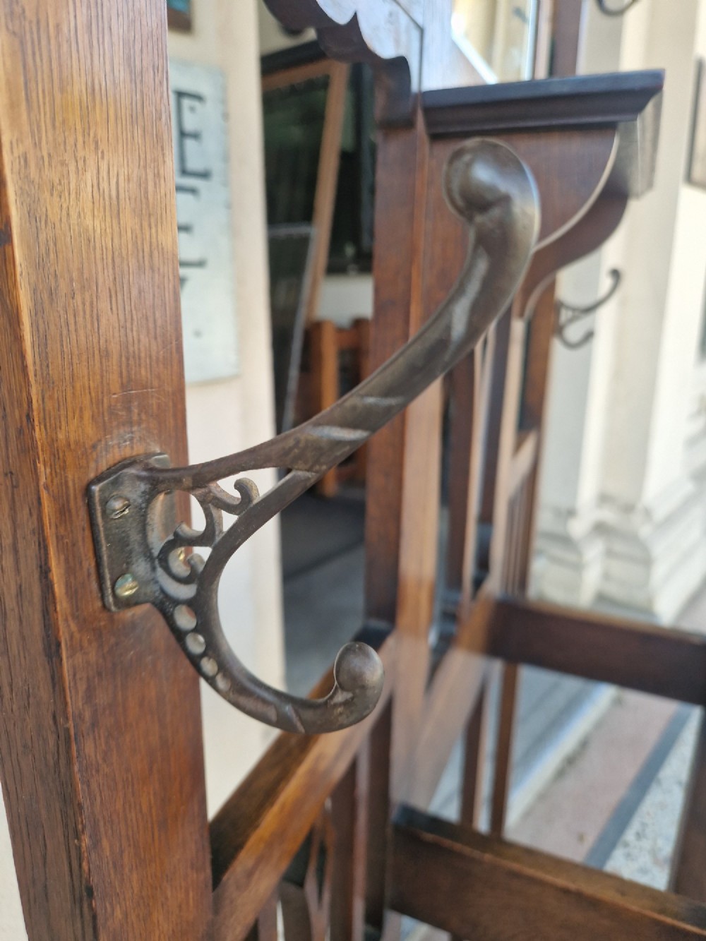 An Art Nouveau oak hall stand featuring a central rectangular mirror, coat hooks, stylized pierced motifs, and an integrated lower umbrella stand with a removable drip tray. View VII