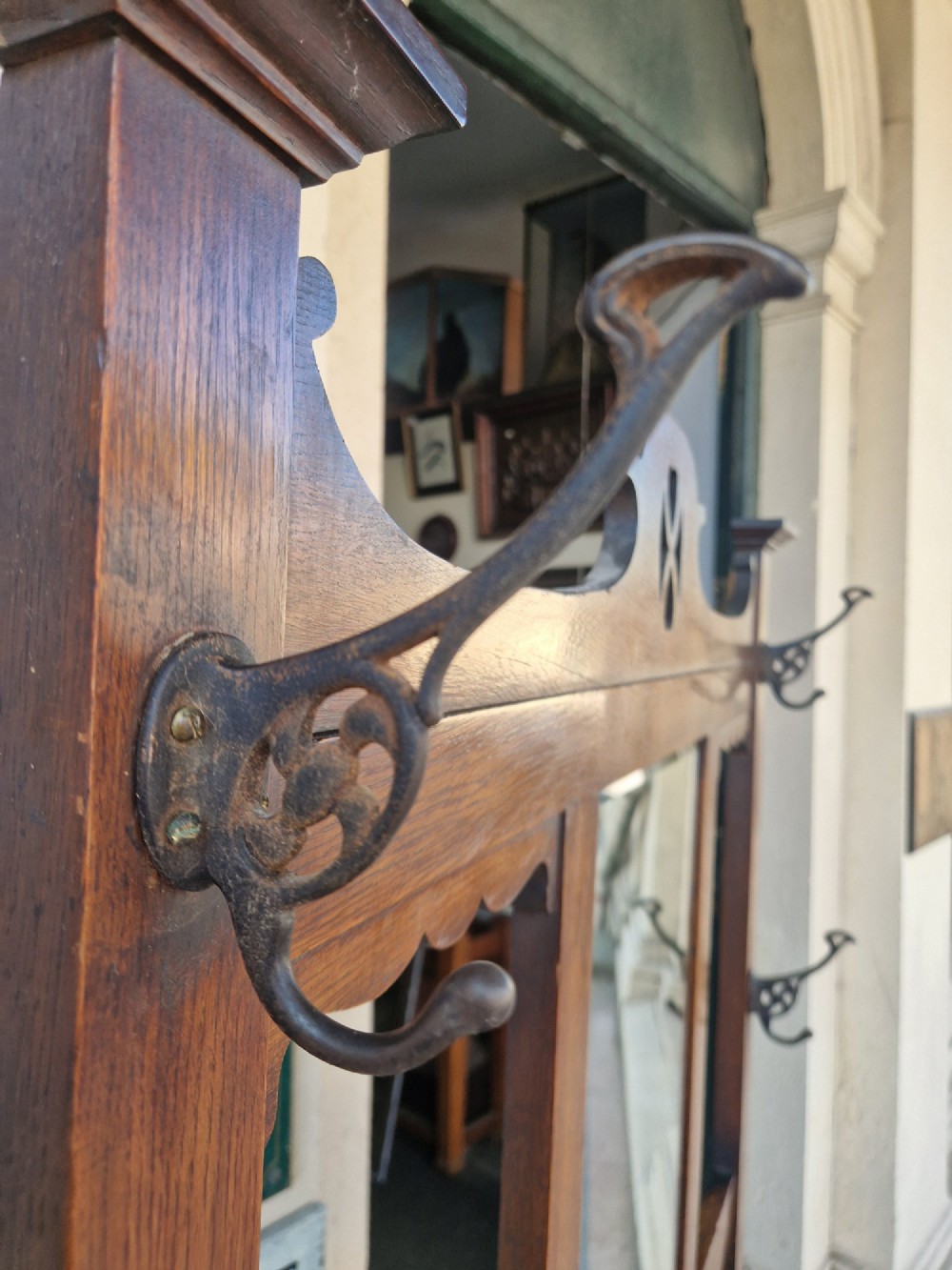 An Art Nouveau oak hall stand featuring a central rectangular mirror, coat hooks, stylized pierced motifs, and an integrated lower umbrella stand with a removable drip tray. View VIII