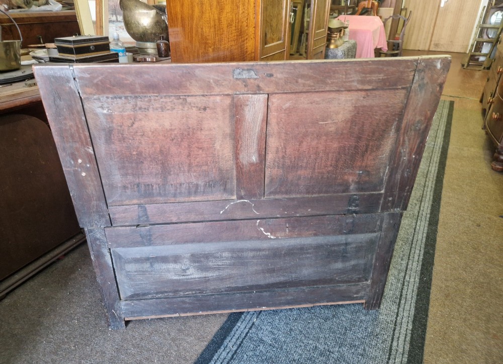 A dark carved oak settle bench with a panelled back, sculpted armrests, and a hinged lid seat above a carved front storage box. View VII