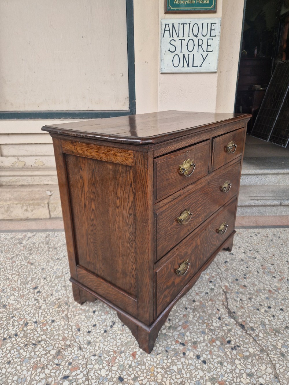 An Edwardian solid oak chest of drawers with two short over two long drawers fitted with decorative brass handles. View III