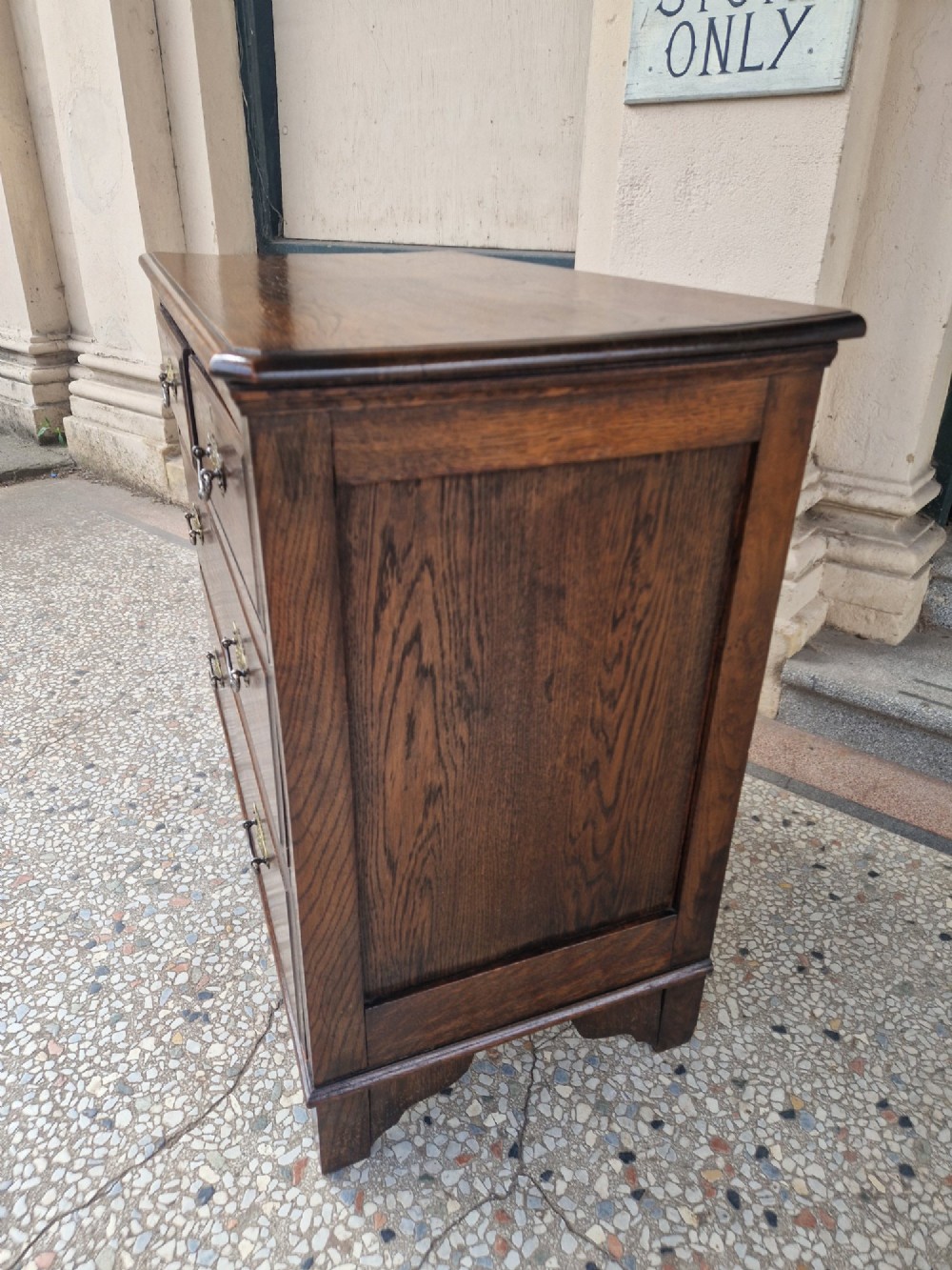 An Edwardian solid oak chest of drawers with two short over two long drawers fitted with decorative brass handles. View IV