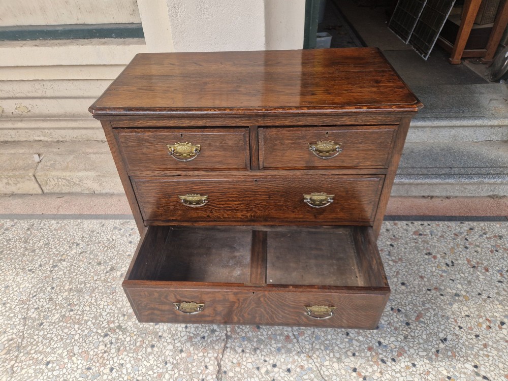 An Edwardian solid oak chest of drawers with two short over two long drawers fitted with decorative brass handles. View VII