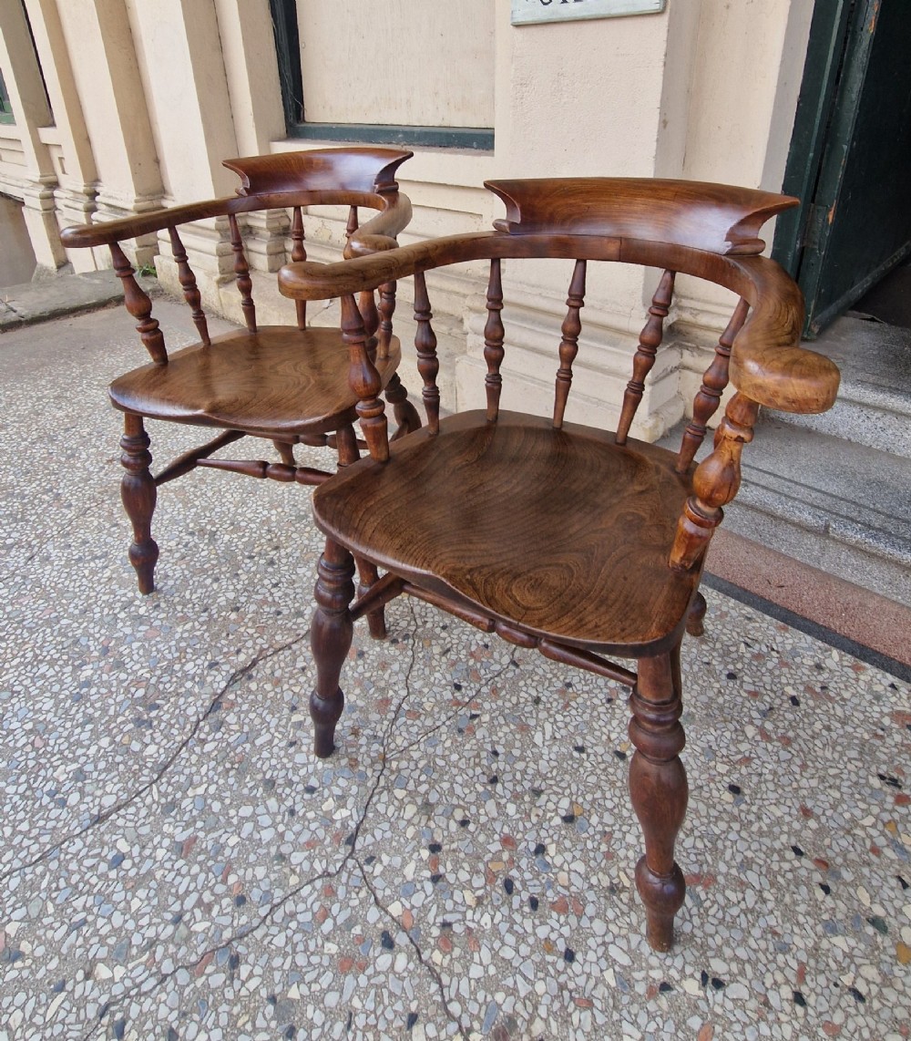 A pair of antique warm brown ash and elm captains armchairs featuring curved horseshoe backrests, turned spindles, shaped saddle seats, and turned legs. View II
