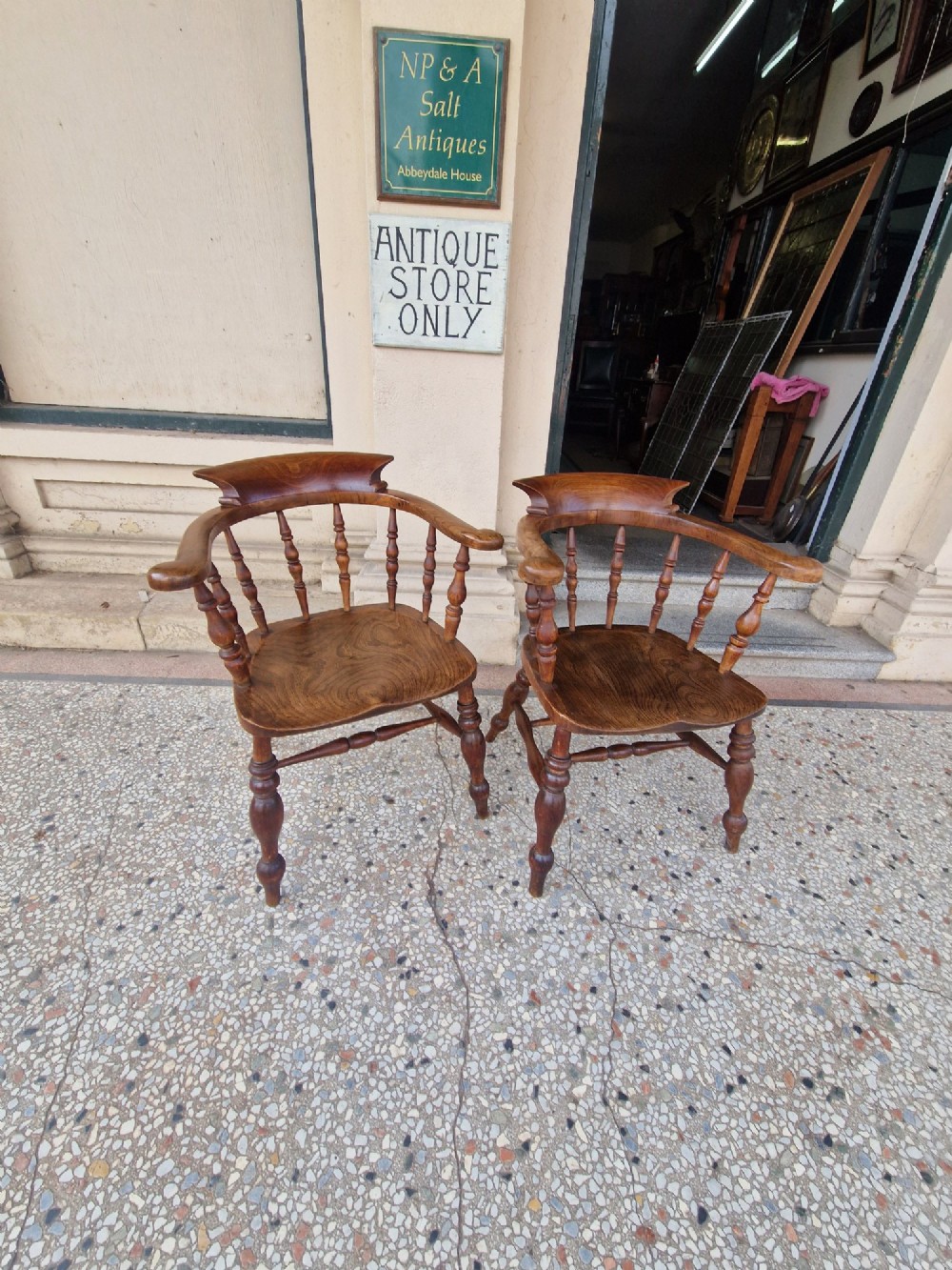 A pair of antique warm brown ash and elm captains armchairs featuring curved horseshoe backrests, turned spindles, shaped saddle seats, and turned legs. View III