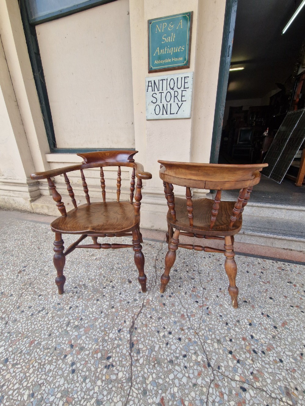 A pair of antique warm brown ash and elm captains armchairs featuring curved horseshoe backrests, turned spindles, shaped saddle seats, and turned legs. View IX