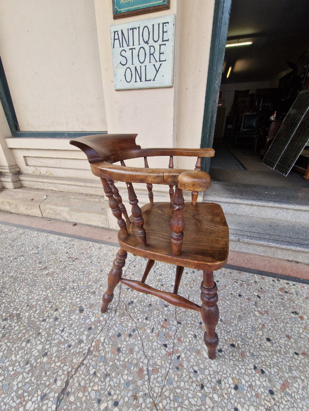 A pair of antique warm brown ash and elm captains armchairs featuring curved horseshoe backrests, turned spindles, shaped saddle seats, and turned legs. View X
