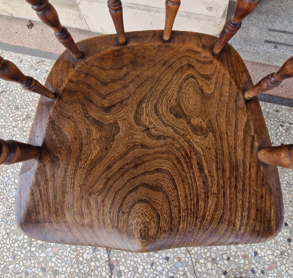 A pair of antique warm brown ash and elm captains armchairs featuring curved horseshoe backrests, turned spindles, shaped saddle seats, and turned legs. View XI
