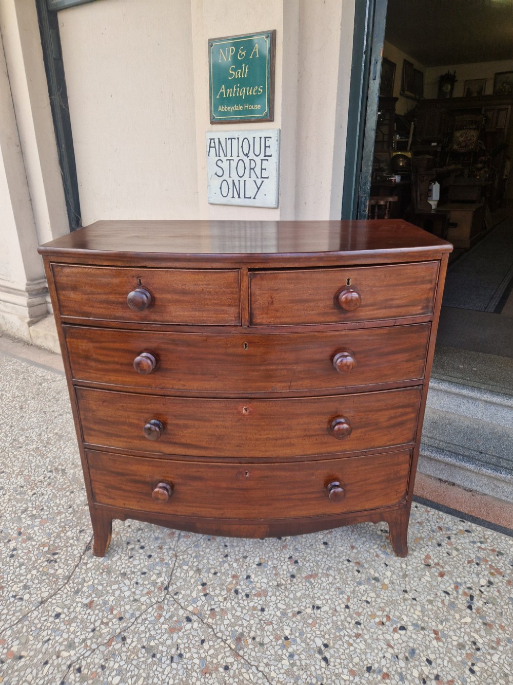 A Georgian mahogany bow-fronted chest of drawers featuring two short over three long graduated drawers with turned wooden knobs and splayed bracket feet.