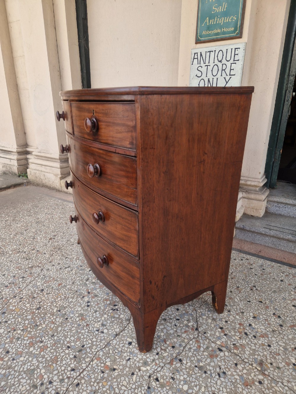 A Georgian mahogany bow-fronted chest of drawers featuring two short over three long graduated drawers with turned wooden knobs and splayed bracket feet. View II