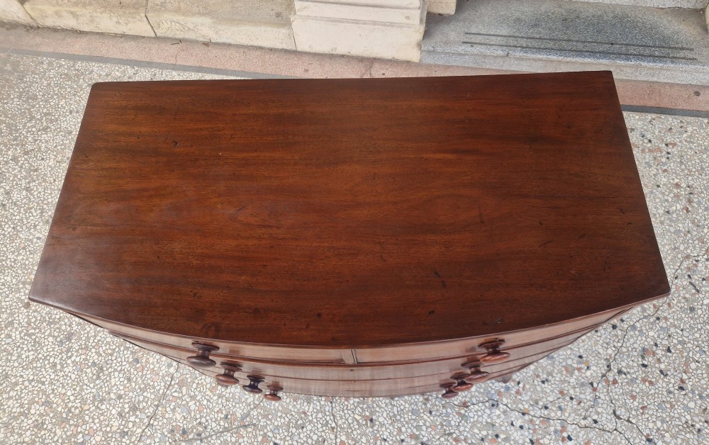 A Georgian mahogany bow-fronted chest of drawers featuring two short over three long graduated drawers with turned wooden knobs and splayed bracket feet. View IV