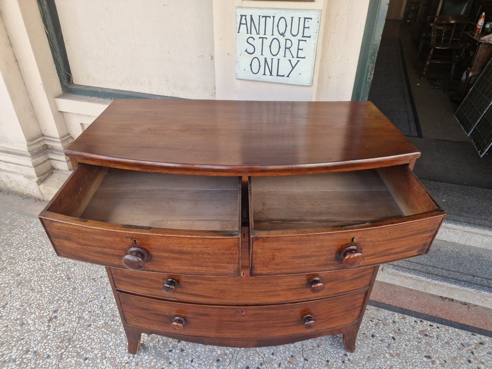 A Georgian mahogany bow-fronted chest of drawers featuring two short over three long graduated drawers with turned wooden knobs and splayed bracket feet. View V