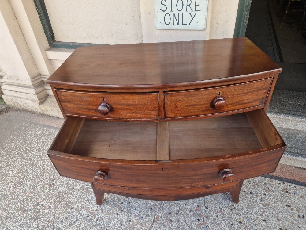 A Georgian mahogany bow-fronted chest of drawers featuring two short over three long graduated drawers with turned wooden knobs and splayed bracket feet. View VI