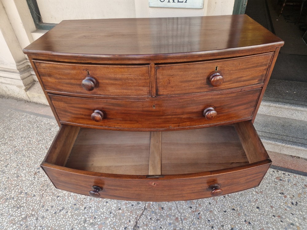 A Georgian mahogany bow-fronted chest of drawers featuring two short over three long graduated drawers with turned wooden knobs and splayed bracket feet. View VII