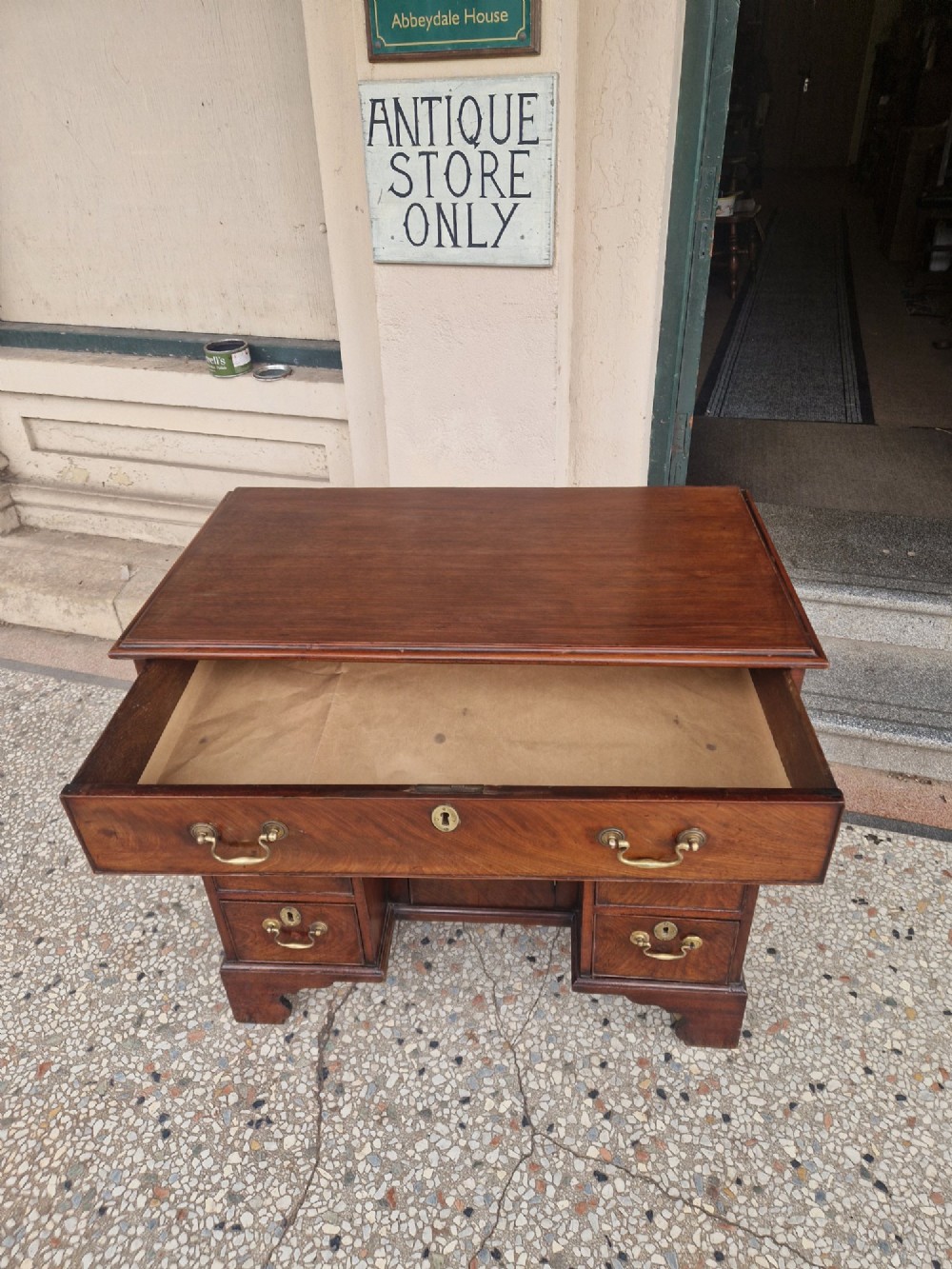 An 18th-century Georgian mahogany kneehole desk featuring a long top drawer, six flank drawers, a central recessed cupboard, brass drop handles, and bracket feet. View IV