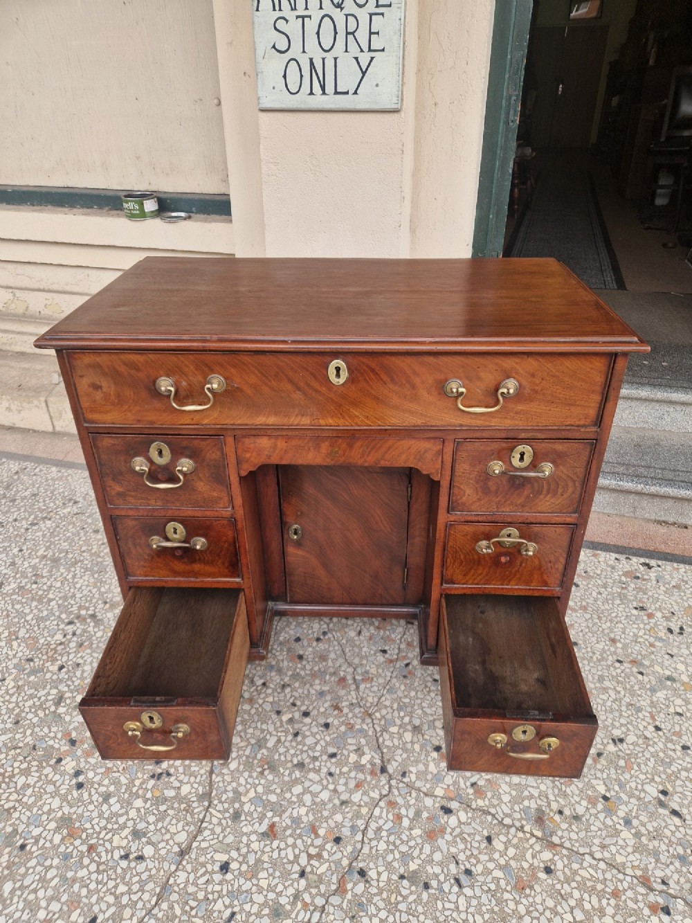 An 18th-century Georgian mahogany kneehole desk featuring a long top drawer, six flank drawers, a central recessed cupboard, brass drop handles, and bracket feet. View VII